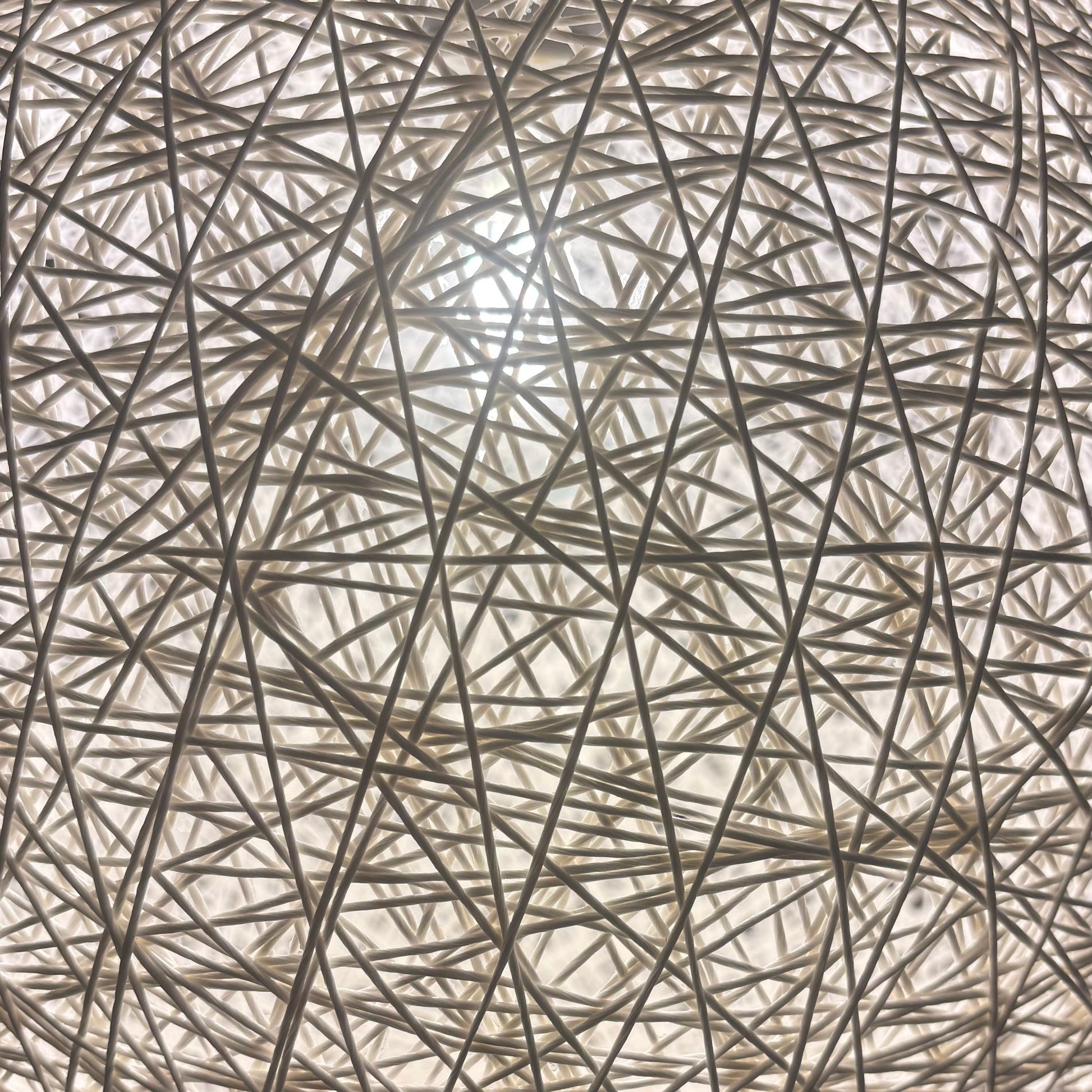 Round lamp with string-like design on a dark background