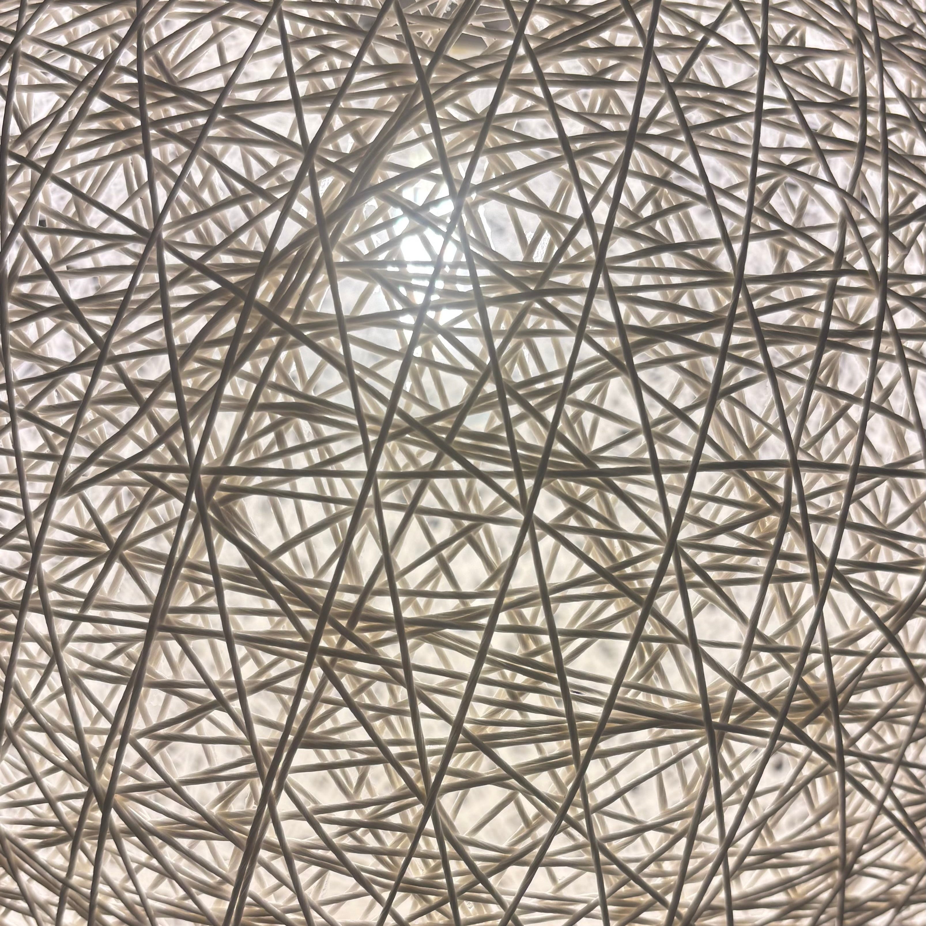 Round lamp with string-like design on a dark background