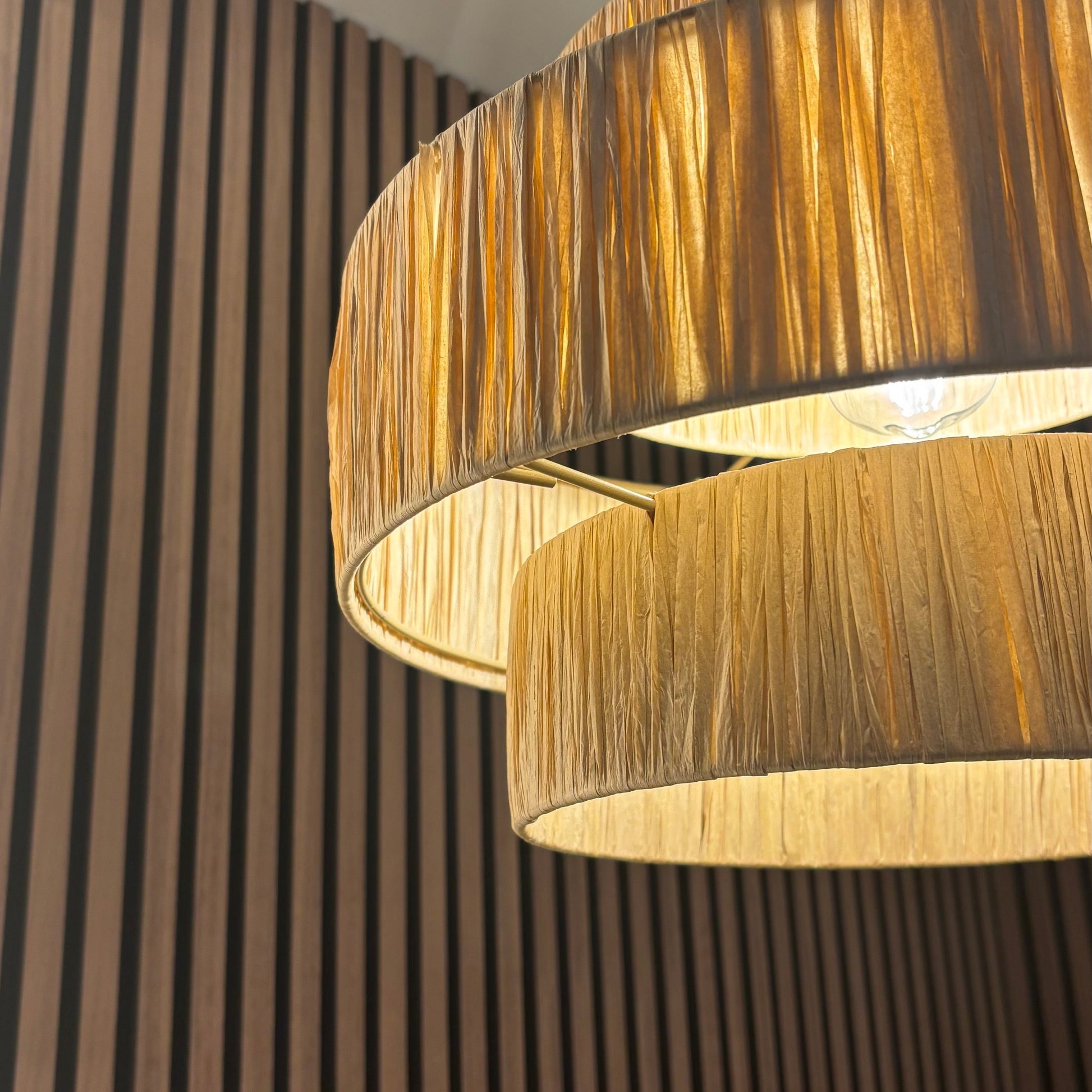 Close-up of a modern pendant light with a wooden finish against a striped wall.