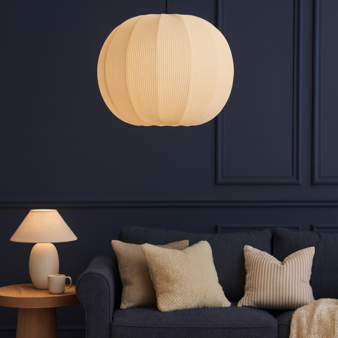 Modern living room with a dark blue sofa, beige pillows, and a round pendant light.