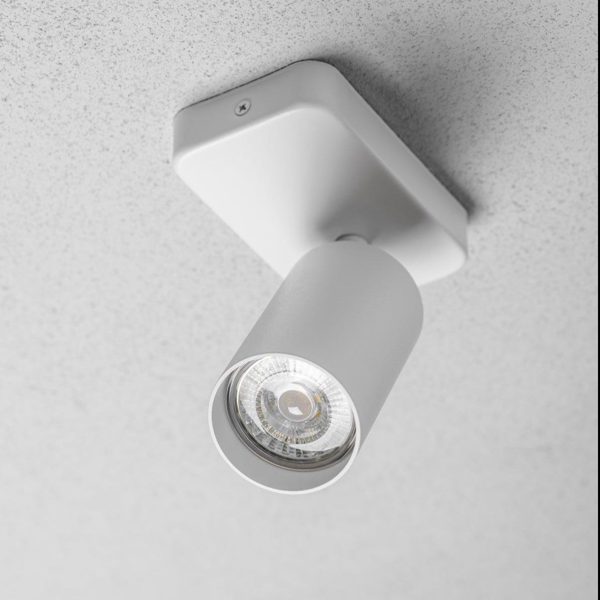 The white Nell lamp consists of a cylindrical spotlight, which can be tilted and adjusted on its own axis. The spotlight is attached to a rectangular bracket, which makes it equally suitable for mounting on walls and ceilings. Made of an aluminium body and powder coated white, the lamp with its simple design fits well into different spaces. 