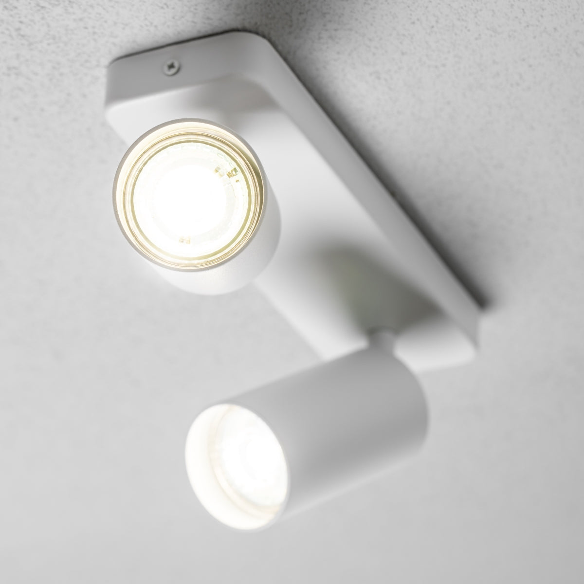 The white Nell lamp consists of two cylindrical spotlights, both of which can be tilted and adjusted on their own axis. The spotlights are attached to a rectangular bracket, which makes them equally suitable for mounting on walls and ceilings. Made of an aluminium body and powder coated white, the lamp with its simple design fits well into different spaces. Whether functional office or cosy home