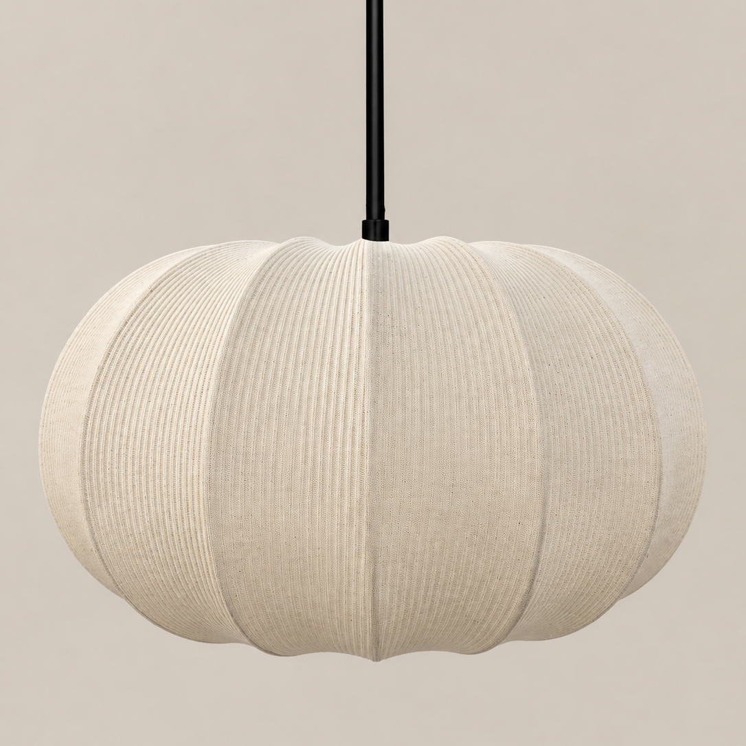 A modern pendant light with a ribbed, pumpkin-shaped shade in a warm off-white fabric, suspended by a slim black cord against a solid beige background.