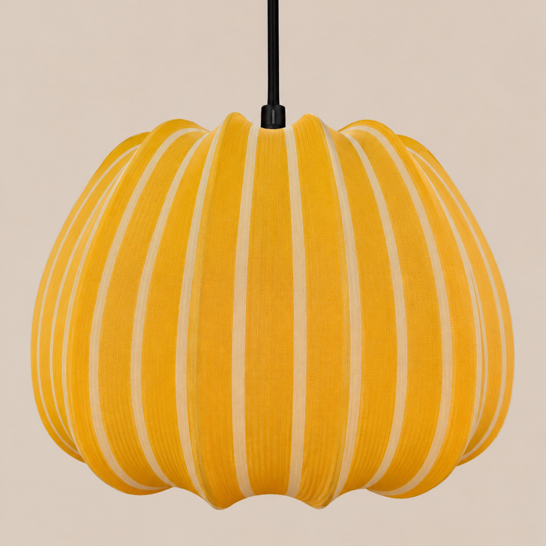A pumpkin-shaped pendant light with vertical yellow and cream stripes, suspended by a black cord against a solid beige background.