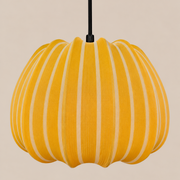 A pumpkin-shaped pendant light with vertical yellow and cream stripes, suspended by a black cord against a solid beige background.