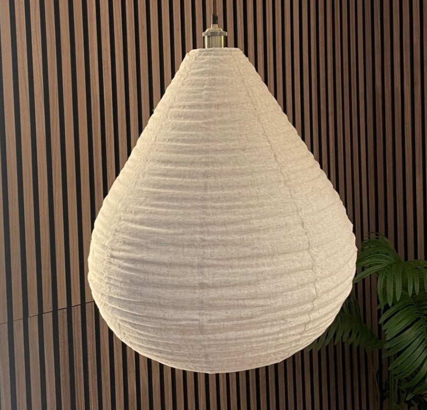 Textured pendant light hanging against a wooden panel background