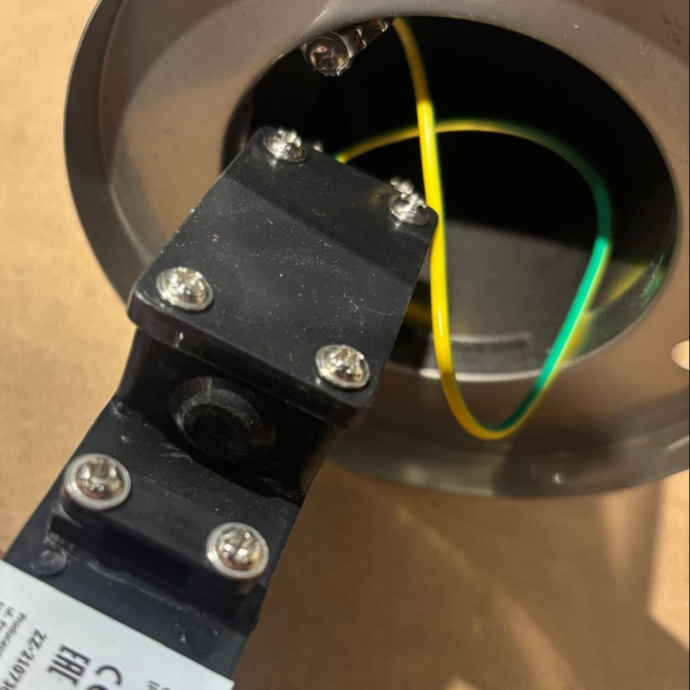 Close-up of a mechanical component with wires and a label on a cardboard background