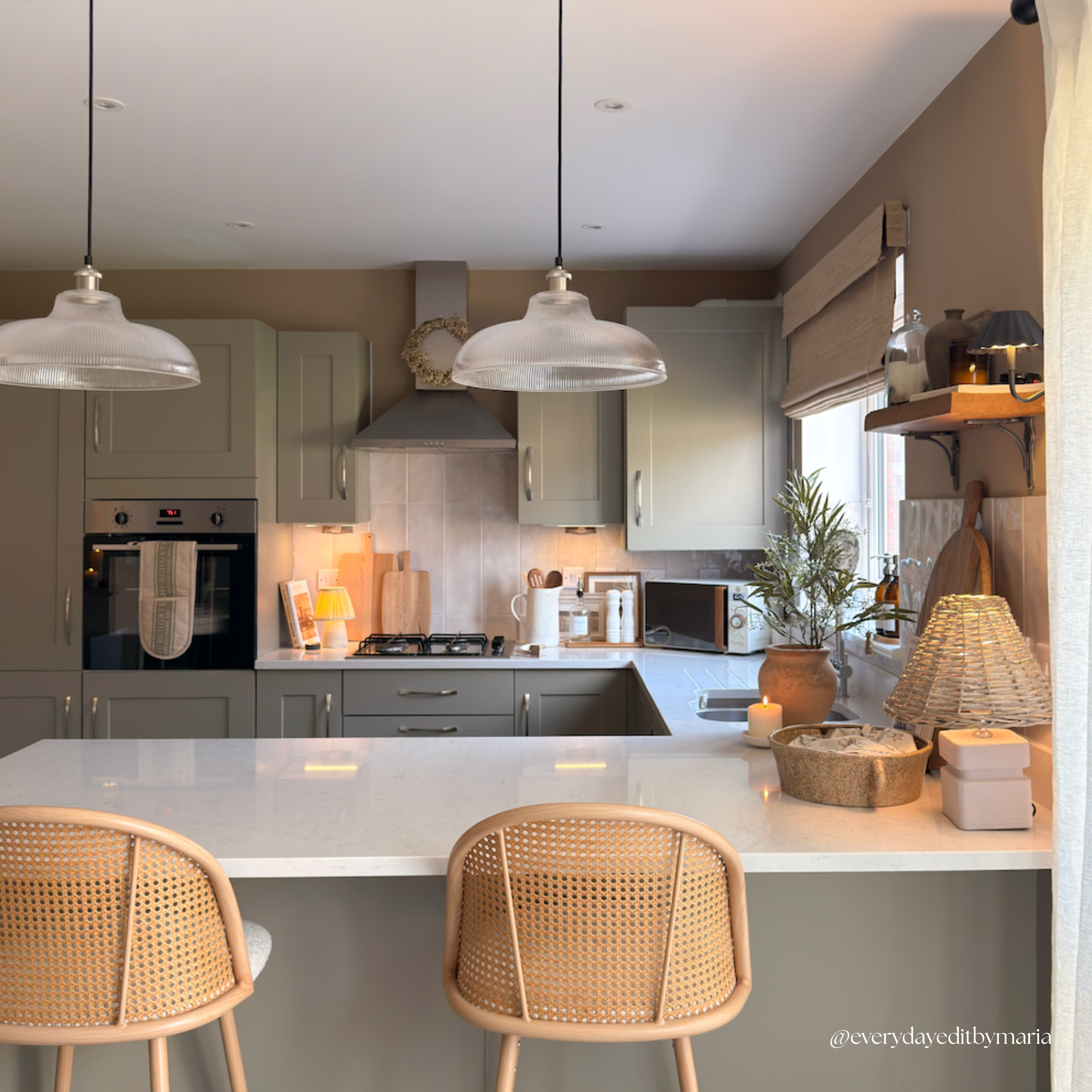 Modern kitchen with white countertops, gray cabinets, and wicker chairs.