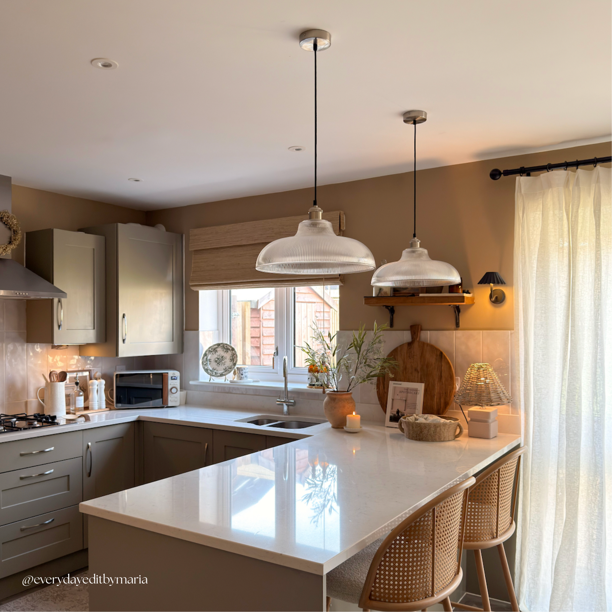 Modern kitchen with white countertops, pendant lights, and a window view.