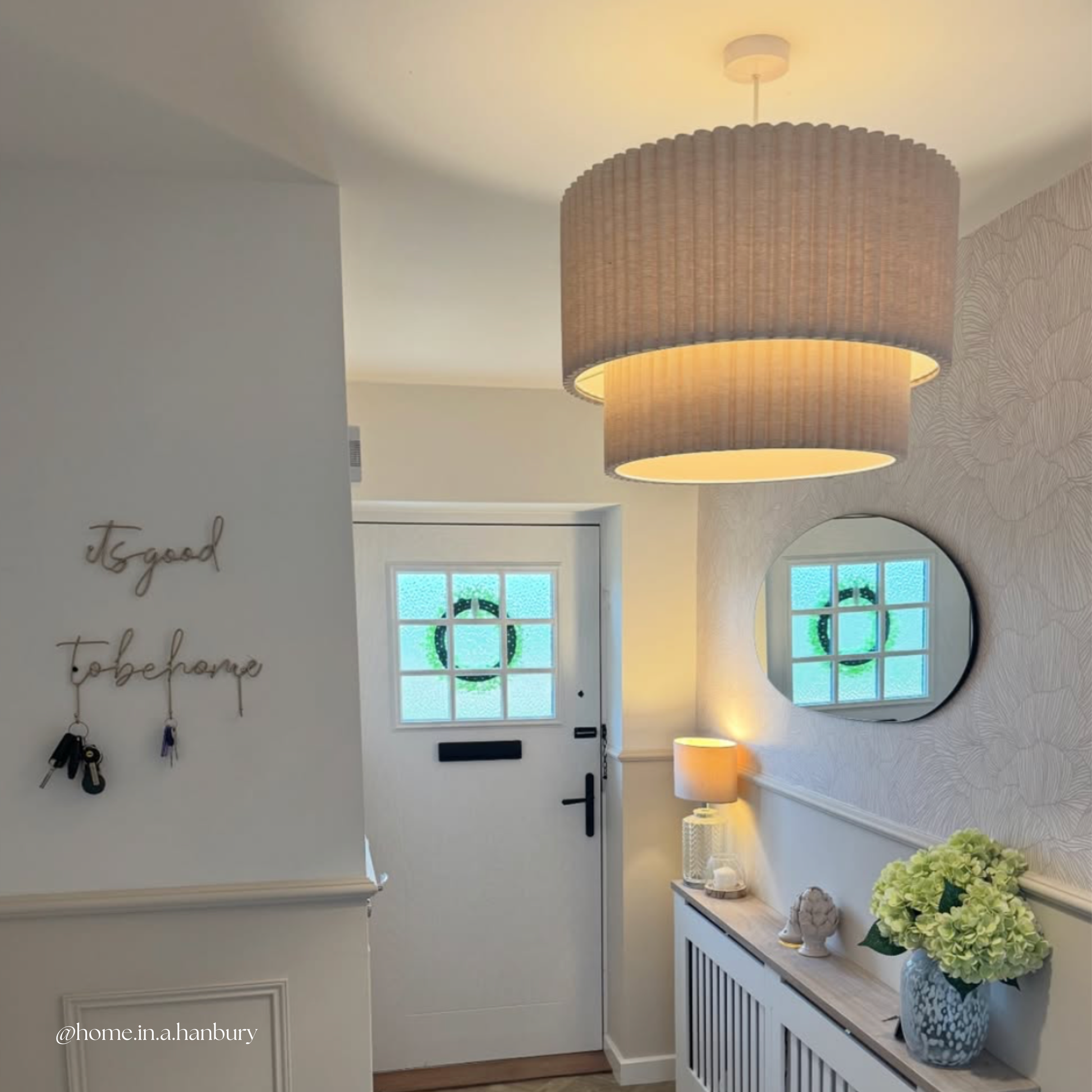 Foyer with a large pendant light, mirror, and decorative items.