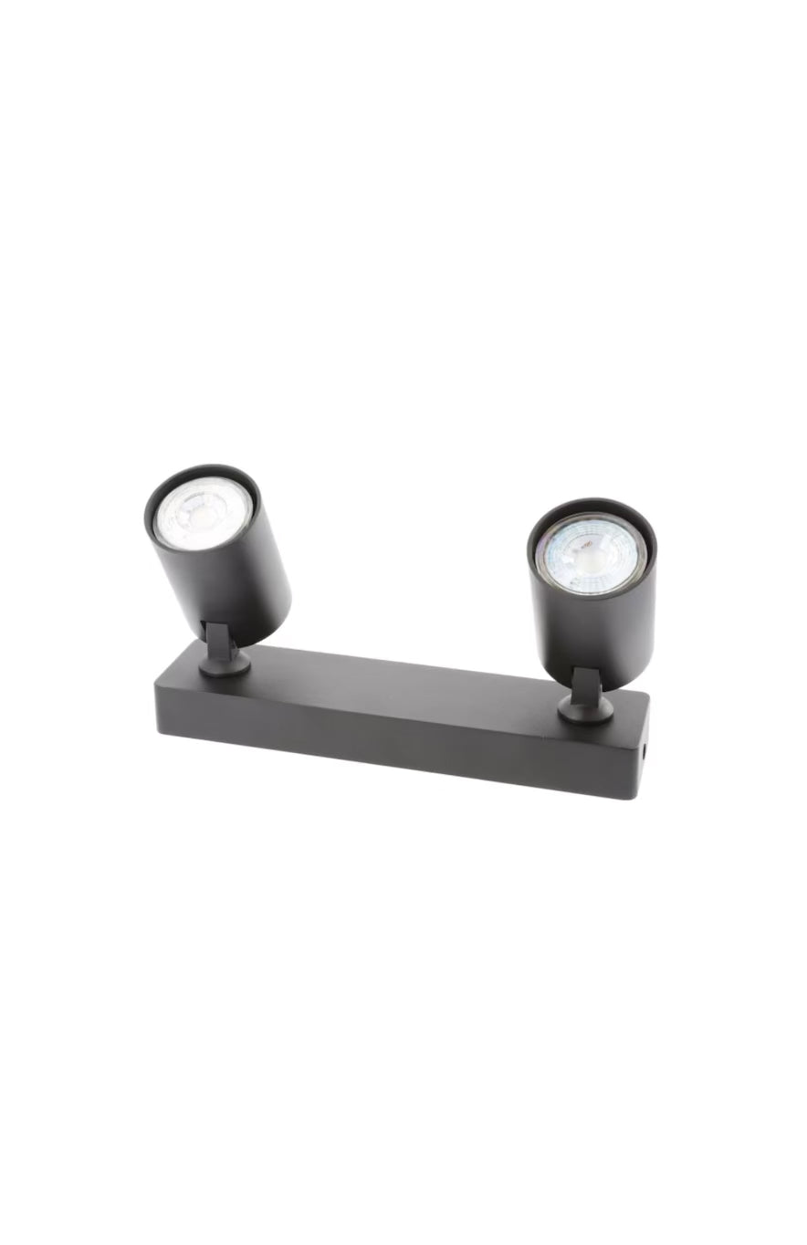 The black Nell twin lamp consists of two cylindrical spotlights, both of which can be tilted and adjusted on their own axis. The spotlights are attached to a rectangular bracket, which makes them equally suitable for mounting on walls and ceilings. Made of an aluminium body and powder coated black, the lamp with its simple design fits well into different spaces.