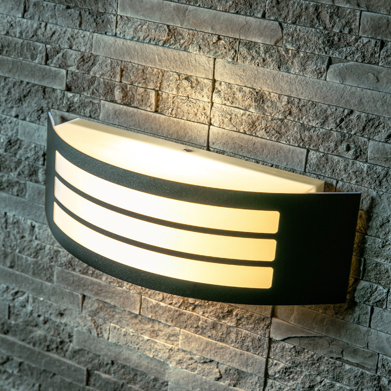 This stylish Striker outdoor light boasts a polycarbonate shade, crafted from stainless steel and adorned with a series of narrow stripes. Its surface disperses the lamp's light uniformly, creating a tranquil, inviting ambiance both indoors and out.