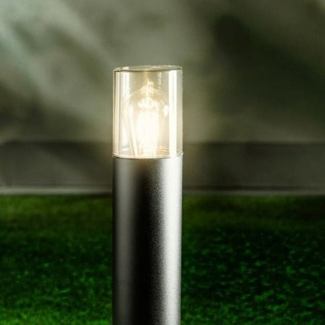This post light features a smoky diffuser, and measures 50 cm high. With its reduced appearance due to its height and colour, this elegant pillar light suits both modern and traditional architecture.