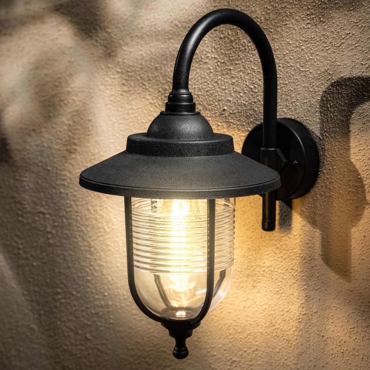 The Jemima black fisherman hooked outdoor wall lantern light is constructed of polycarbonate and features an attractive design inspired by traditional lighting styles. This lantern wall light is a great choice for illuminating doorways and porches, creating a warm and inviting look and a safe environment. With an IP44 safety rating, the Jemima garden wall light is suitable for mounting on outdoor walls.