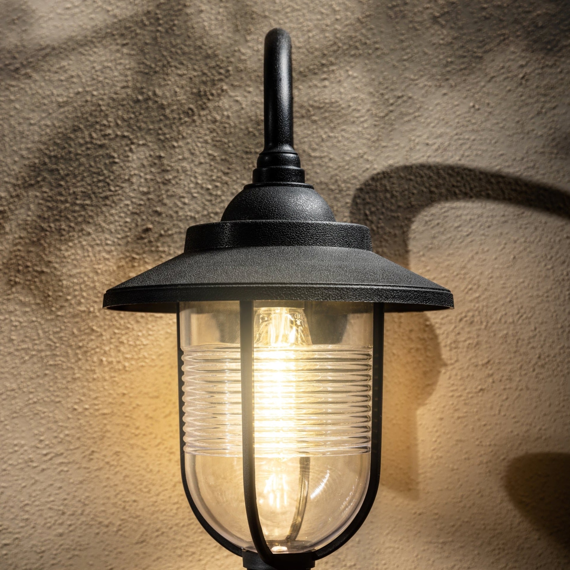 The Jemima black fisherman hooked outdoor wall lantern light is constructed of polycarbonate and features an attractive design inspired by traditional lighting styles. This lantern wall light is a great choice for illuminating doorways and porches, creating a warm and inviting look and a safe environment. With an IP44 safety rating, the Jemima garden wall light is suitable for mounting on outdoor walls.