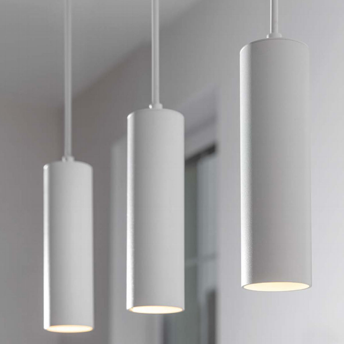 High-quality white ceiling triple hanging spotlight pendant. A cylinder pendant with a modern and sleek design would add a huge element of style and class to any room. Made of aluminium with a powder coat finish. Height can be adjusted during installation.