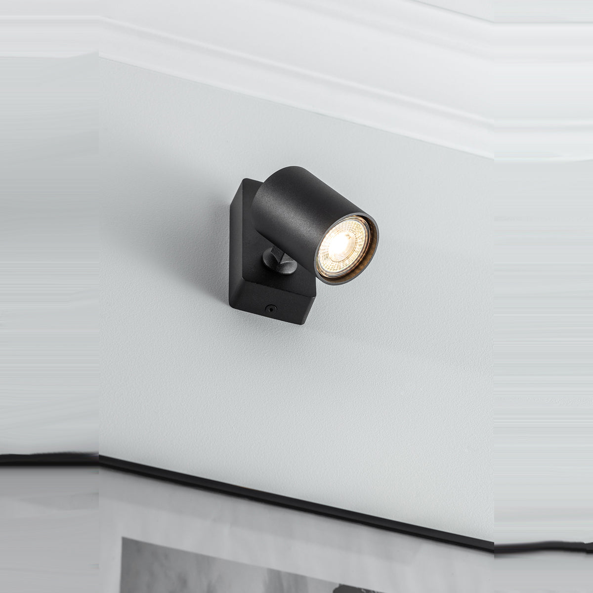 The black Nell lamp consists of a cylindrical spotlight, which can be tilted and adjusted on its own axis. The spotlight is attached to a rectangular bracket, which makes it equally suitable for mounting on walls and ceilings. Made of an aluminium body and powder coated black, the lamp with its simple design fits well into different spaces. Whether functional office or cosy home - the timeless lamp is an perfect for many types of use.