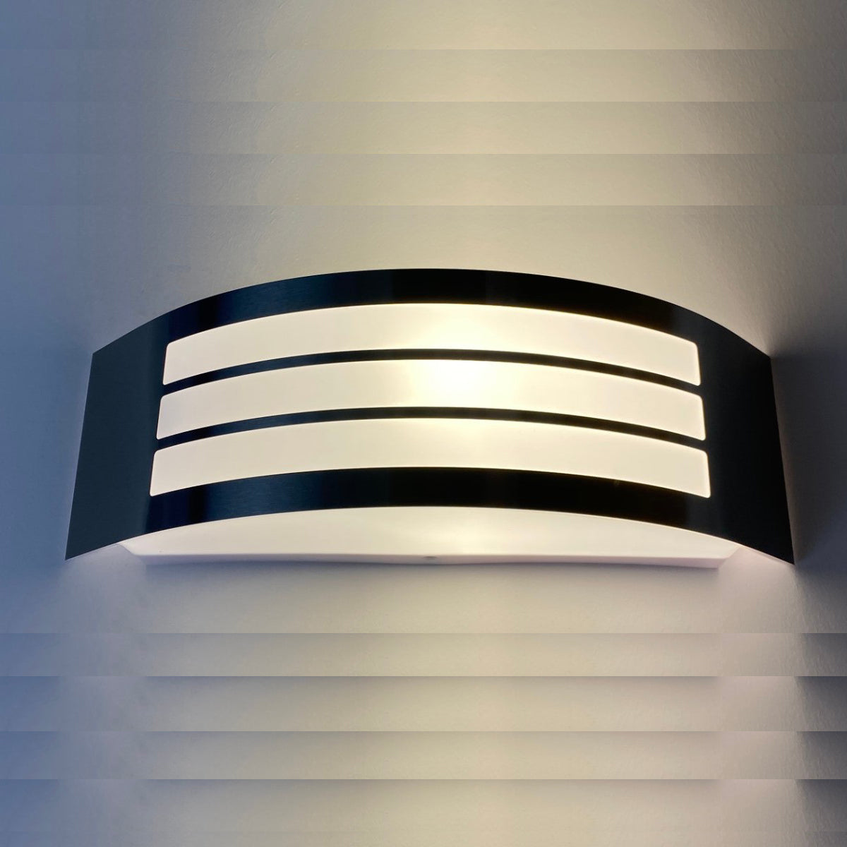 This stylish Striker outdoor light boasts a polycarbonate shade, crafted from stainless steel and adorned with a series of narrow stripes. Its surface disperses the lamp's light uniformly, creating a tranquil, inviting ambiance both indoors and out.